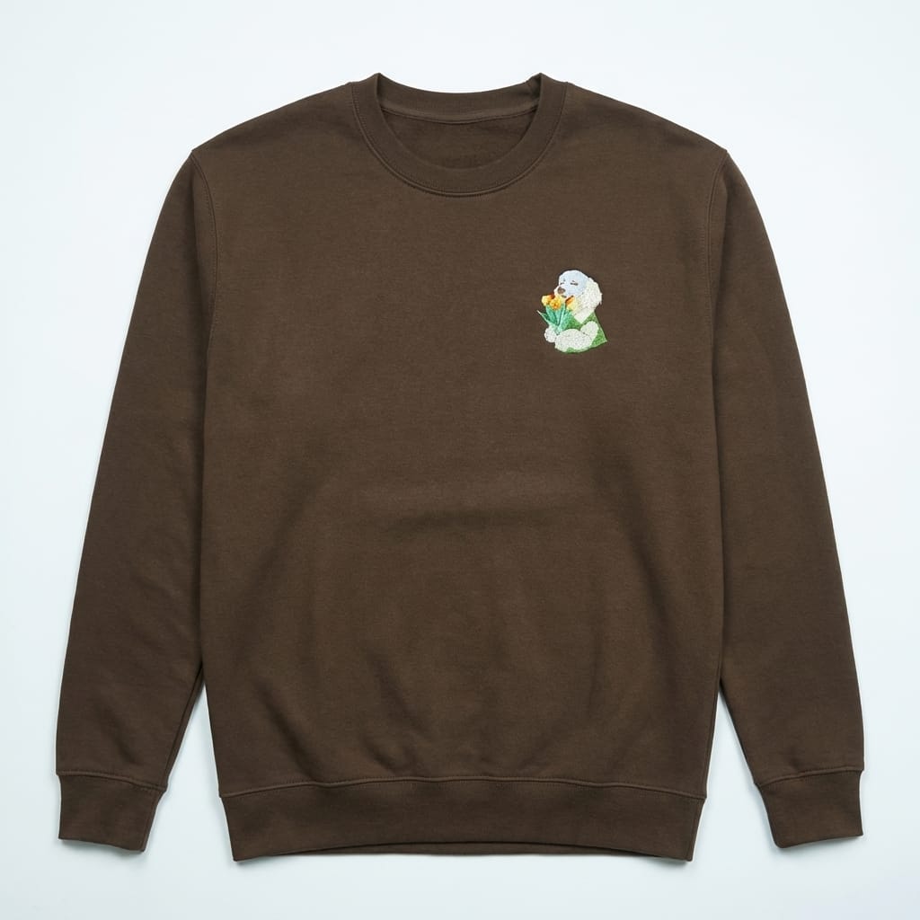 Brown sweatshirt with a small embroidered design on the chest against a light gray background